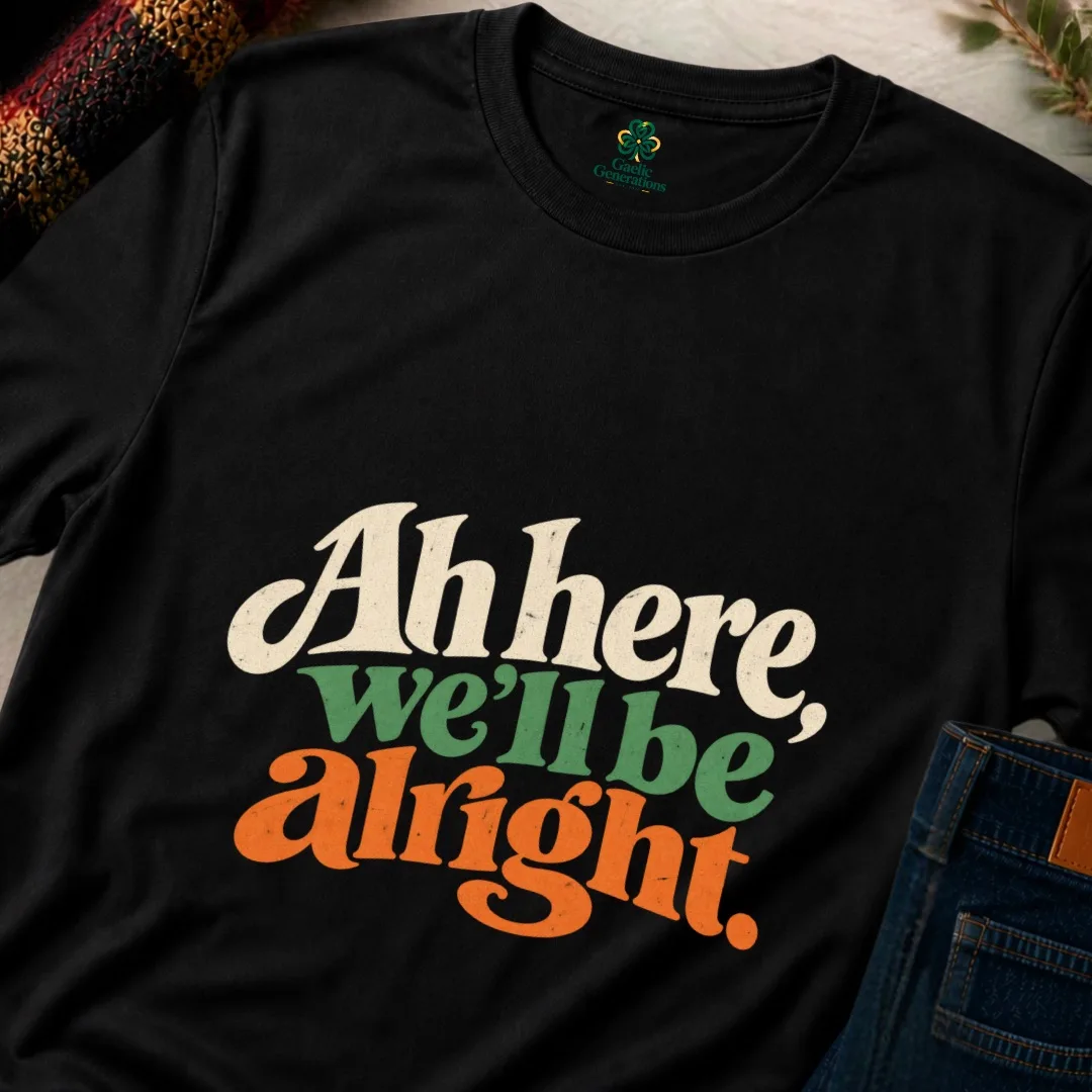 Close-up of the black Ah Here, We’ll Be Alright Irish T-Shirt showing the cream, green and orange design