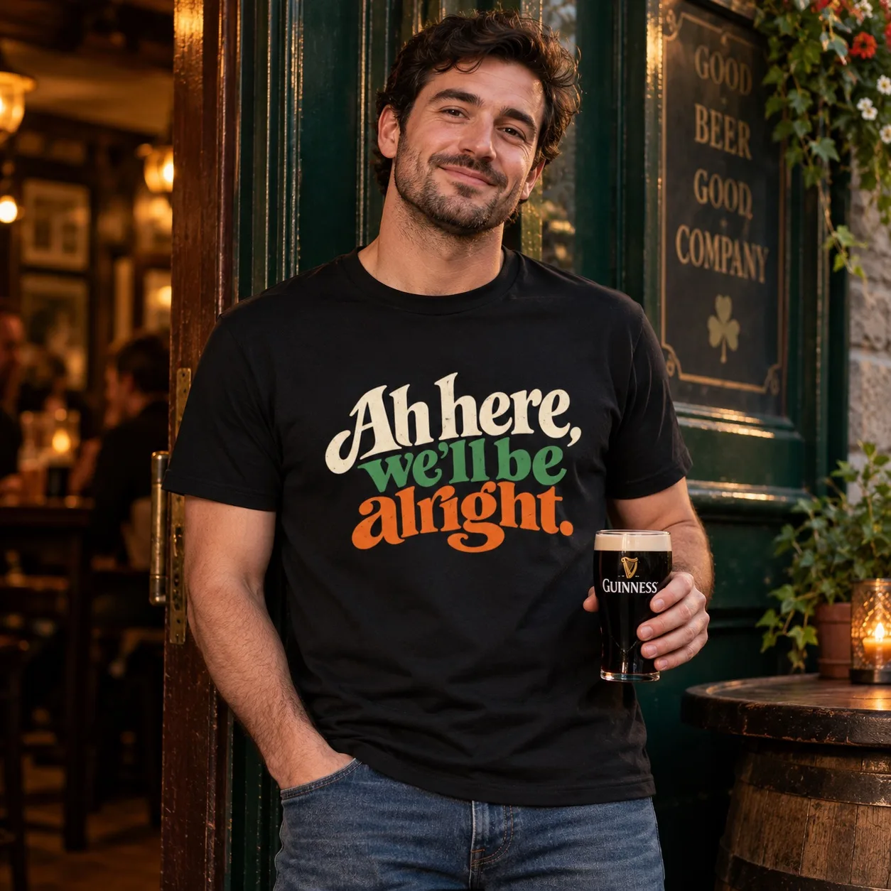Man wearing the black Ah Here, We’ll Be Alright Irish T-Shirt outside an Irish pub
