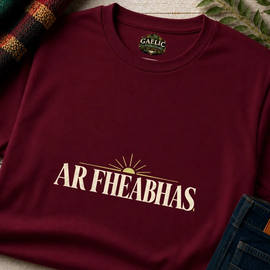 Close-up of maroon Ar Fheabhas Irish language T-shirt with cream typography and sunrise design