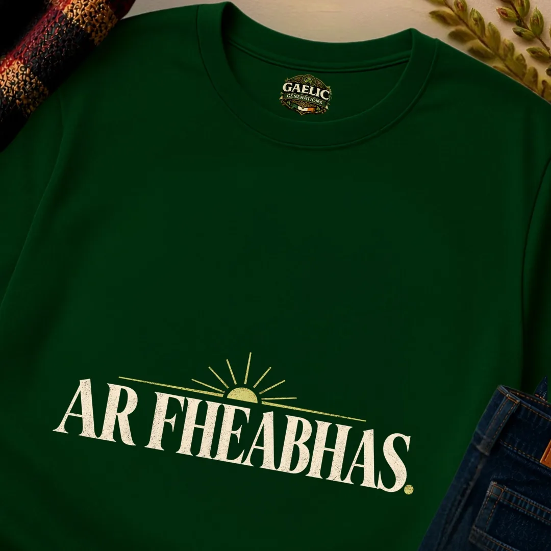 Close-up of forest green Ar Fheabhas Irish T-shirt with cream vintage typography and sunrise graphic