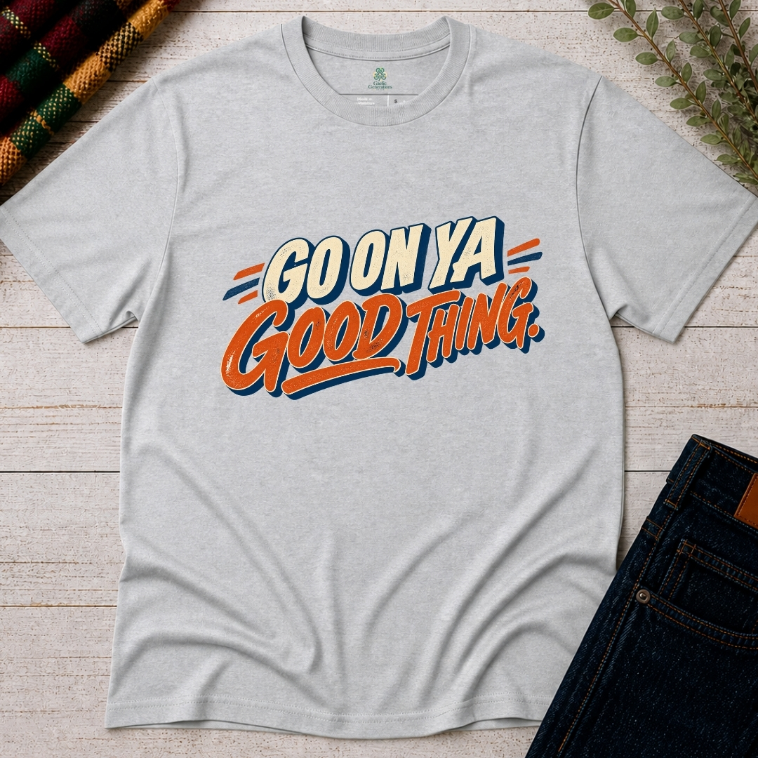 Ash grey Go On Ya Good Thing Irish saying T-shirt with vintage cream lettering, orange script and navy accents, displayed flat on rustic wood