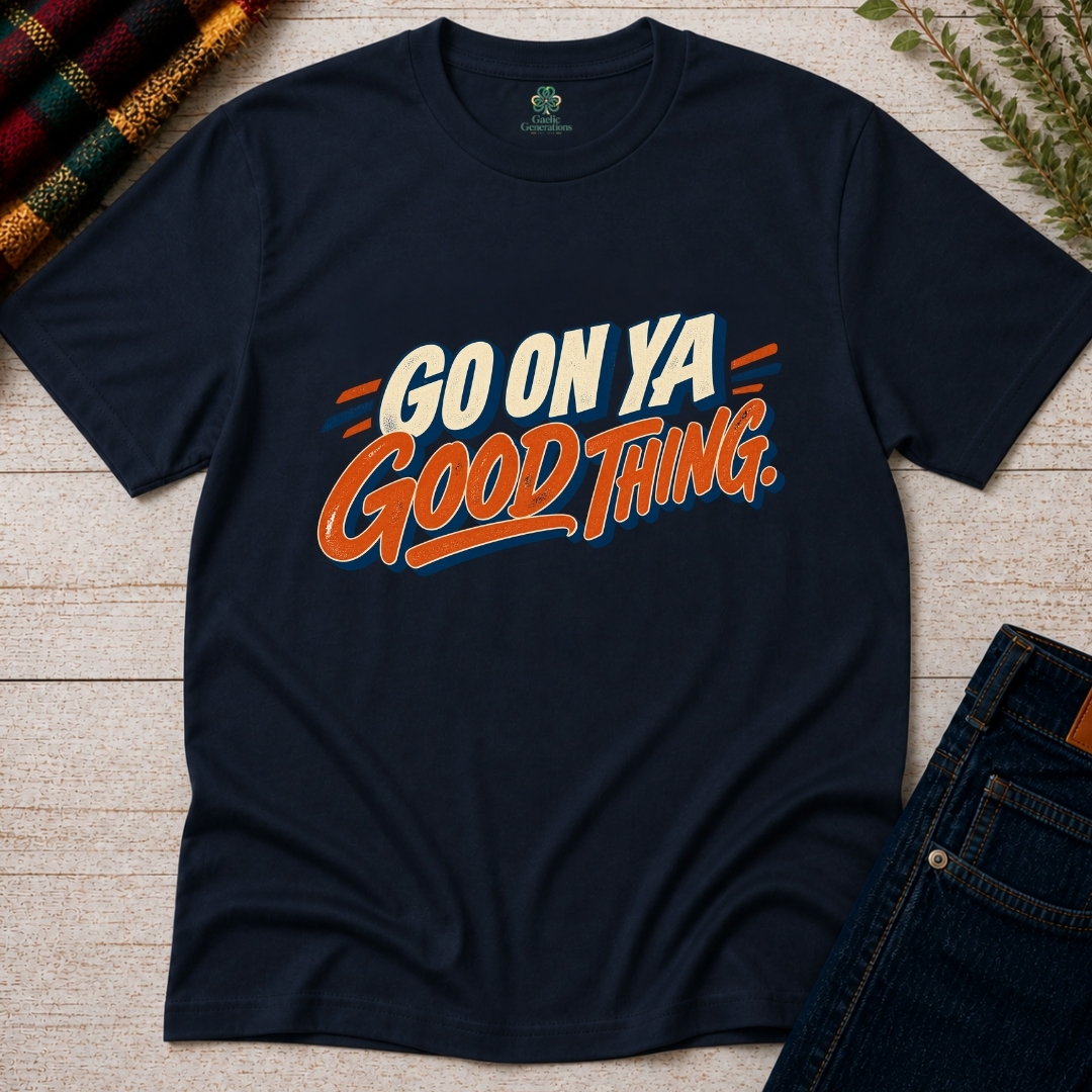 Navy Go On Ya Good Thing Irish T-shirt displayed flat on rustic wood, featuring cream block lettering and orange retro script