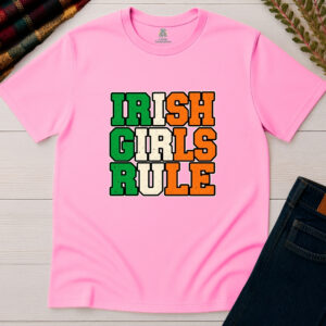 Light pink Irish Girls Rule T-shirt displayed flat on a wooden background, featuring bold green, cream and orange vintage collegiate lettering