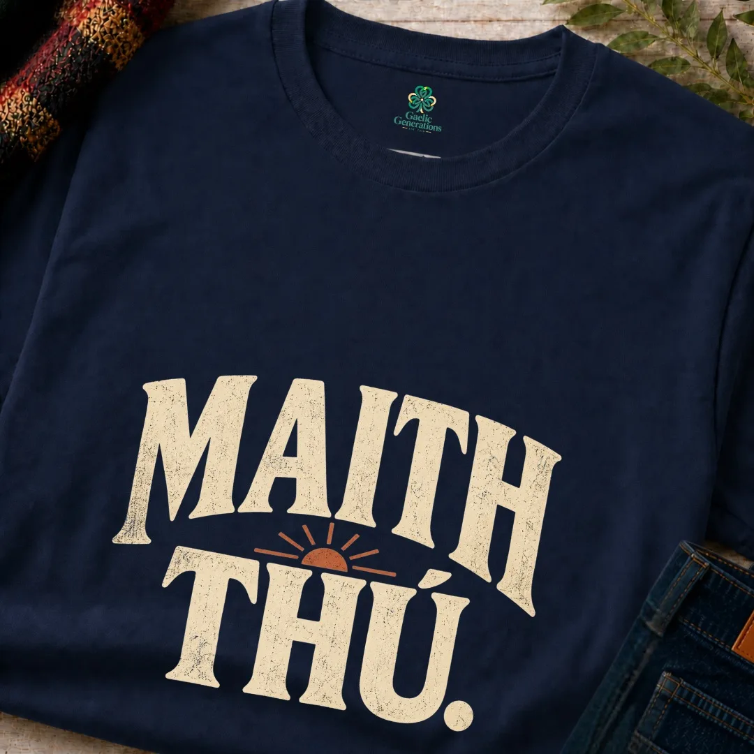 Close-up of navy Maith Thú Gaeilge T-shirt with distressed cream typography and sunrise design