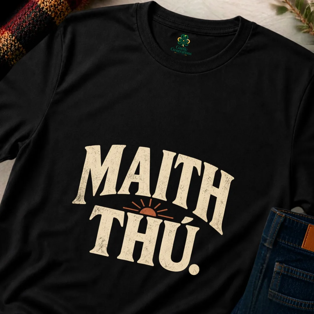 Close-up of black Maith Thú T-shirt showing distressed cream typography and vintage sunrise detail