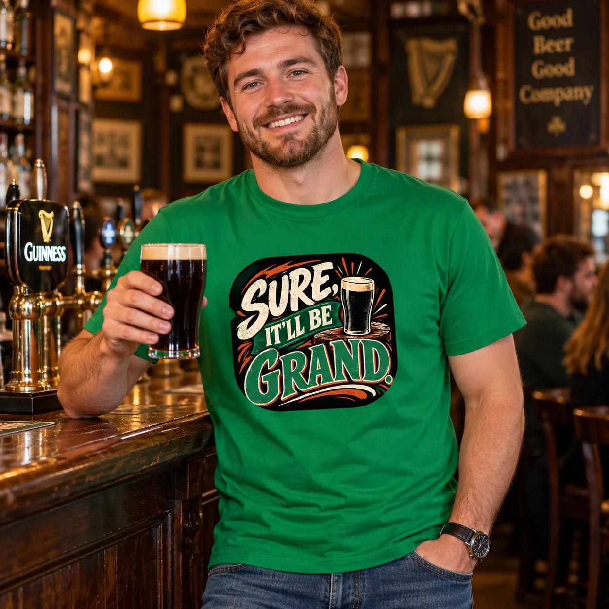 Man wearing the Irish Green Sure, It’ll Be Grand Irish T-Shirt while holding a pint in an Irish pub
